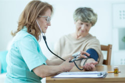 nurse checking the blood pressure of an elder